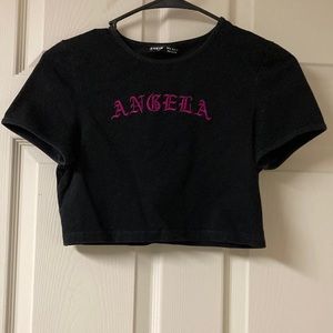 A black crop top from SHEIN size medium on the Front of the shirt it says angel